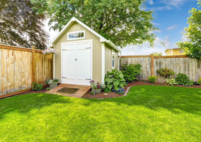 Fenced in backyard with a shed and lush green lawn